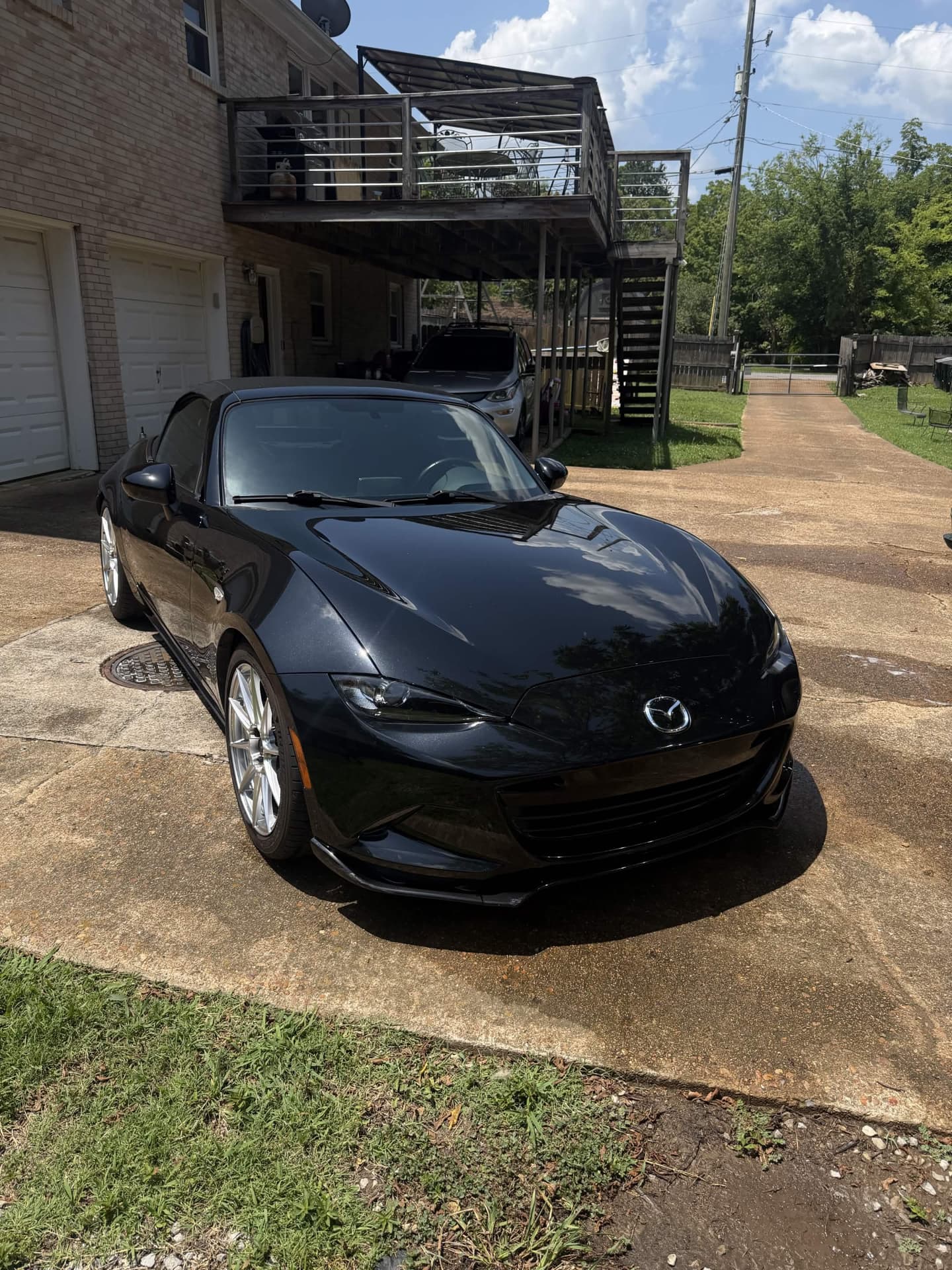 Black Miata paint polished to a mirror finish, reflecting the sky across the hood.